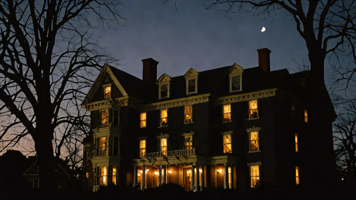 Fachada de la emblemática casa de estilo colonial holandés en Amityville al anochecer.