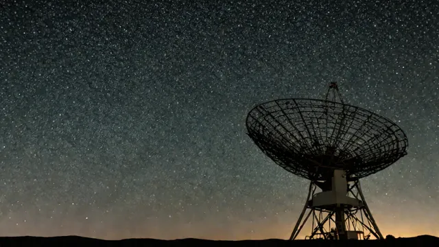 Gran radiotelescopio apuntando hacia la Vía Láctea en un cielo nocturno estrellado.